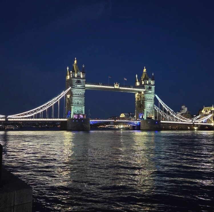 Tower Bridge floodlit at night, beside the ancient fortress.